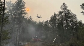 This image provided by the The Michigan Department of Natural Resources shows emergency personnel, aircraft and heavy equipment being used to suppress the wildfire near Grayling, Mich., June 3, 2023.