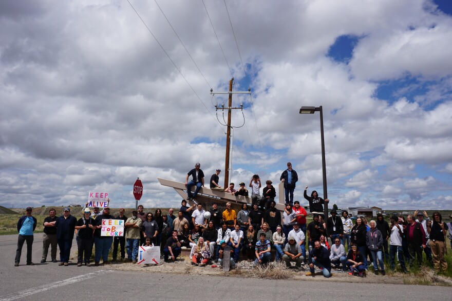 A crowd of people gather together to pose for a photo, holding signs like "keep job corps."