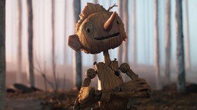 A still image from the Netflix production of "Pinocchio" shows the title character, a wooden puppet come to life walking through the woods.