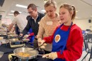 A volunteer helps Carley Zagalik prepare french toast.