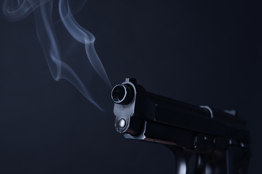 close up of a smoking gun with a dark background
