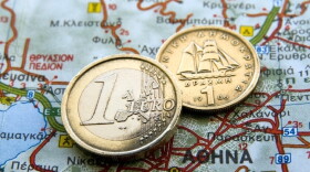 A euro coin and an old Greek drachma rest on a map of Greece. Some observers have predicted a Greek exit from the eurozone.
