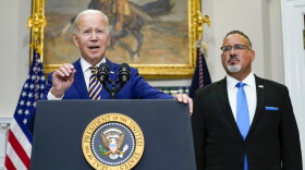 President Joe Biden speaks about student loan debt forgiveness in the Roosevelt Room of the White House, Wednesday, Aug. 24, 2022, in Washington. Education Secretary Miguel Cardona listens at right.