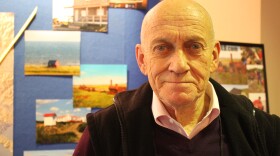 Richard Beneville stands in front of the Nome table at the Alaska Travel Industry Association’s convention at Juneau’s Centennial Hall. (Photo by Lisa Phu/KTOO)