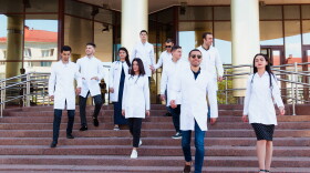 A friendship group of European medical students presented outdoor against the university door on the steps.