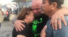 Lorenzo Flores and Terri Smith are comforted by a friend. Flores and Smith learned their friend Joann Ward and two of her children were killed in the shooting. (Joey Palacios/Texas Public Radio)