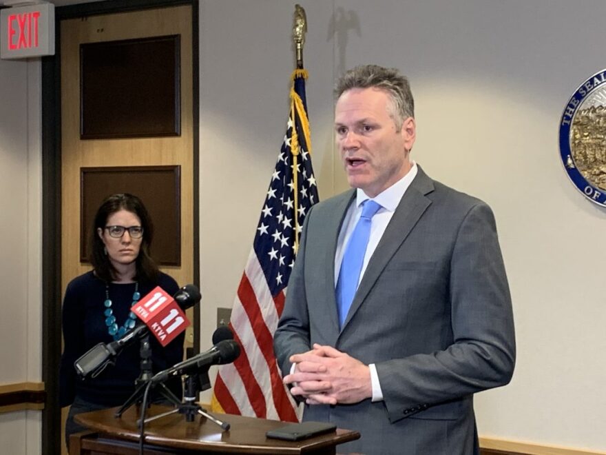 Gov. Mike Dunleavy talks to reporters at a press conference about the novel coronavirus on Monday, March 9, 2020, while Alaska Chief Medical Officer Anne Zink stands in the background.