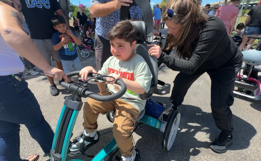 Marcel Rodriguez is 11 years old. He gets fitted for his bike by Martha Mankin, a physical therapist at Lee Health Children's Rehabilitation Center -Golisano Children's Health Center. Robbie’s Riders, Grampy’s Charities and Sanibel Captiva Community Bank. The three sponsors presented custom-made, adaptive bicycles and tricycles to local special needs children. Eight adaptive tricycles, worth nearly $3,000 each, were given out on Friday, March 20, 2026. Marcel has Duchenne muscular dystrophy, a genetic disorder that causes progressive muscle weakness.