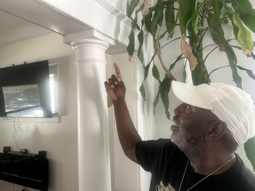 Wilson points towards a crack above a pillar he has chalked and painted over multiple times.