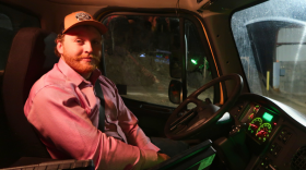 A man sits in the driver's seat of a snowplow.