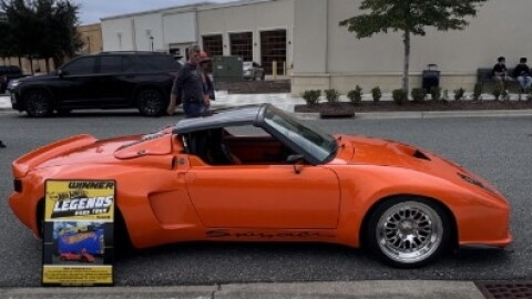 This orange Porsche Spyder was on display at the Sixth Annual International Car Show at Butler Town Center in Gainesville on Saturday, Oct. 17, 2026. The sign at left identifies it as having been selected for the 2025 Hot Wheels Legends Tour. (Samuel Rappoport/WUFT News)