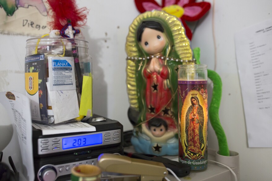 A small shrine to the Virgin of Guadalupe sits behind the counter at the <em>tienda</em> that Fabiola Escamilla owns in Galax, Va. Escamilla is a DACA recipient. Despite living in Galax for much of her life and raising her two sons there, she is still very concerned about her immigration status.