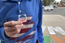 A man wearing a blue shirt with an American flag on it holds up a sticker that says “I voted today.”