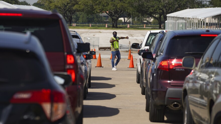 An election worker guides voters in cars at a drive-through voting site in Houston on Oct. 7.