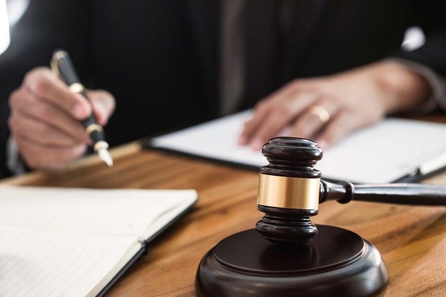 A judge signs papers with a gavel on the desk.