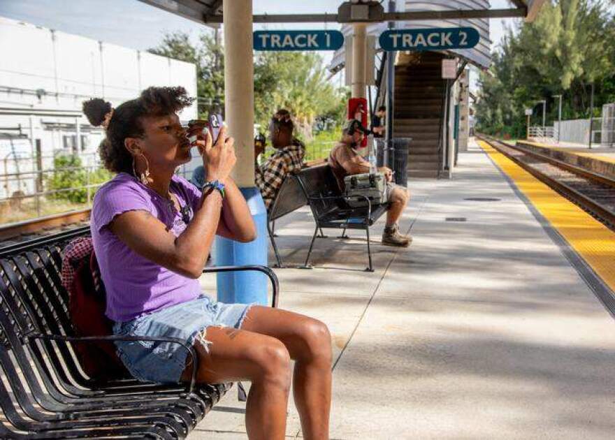 Z Spicer puts on eyeliner while waiting for the Tri-Rail as part of their commute to work in Little Havana.