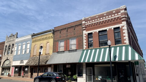 The view of a few shops in downtown Mexico, Missouri. The buildings appear older with unique facades of different colored brick. 