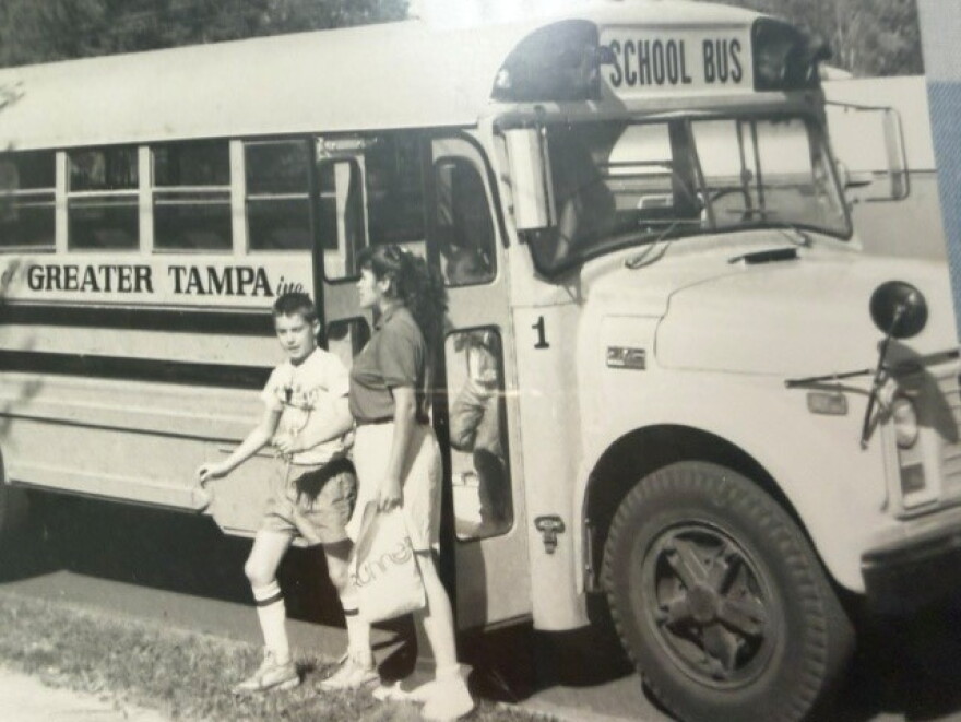 Black and white photo of people getting off a school bus 