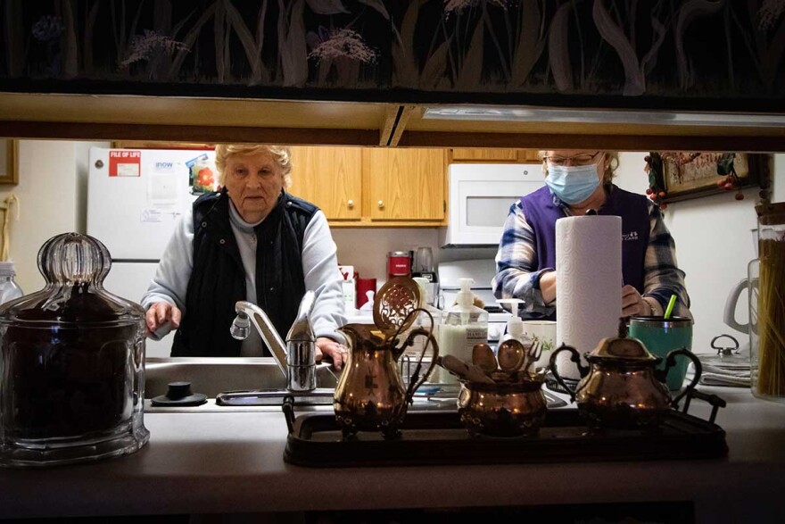 a home healthcare aide works with an elderly woman in her kitchen.