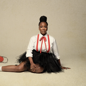 Photo of Tanika Charles sitting on the ground with a red bike to her right