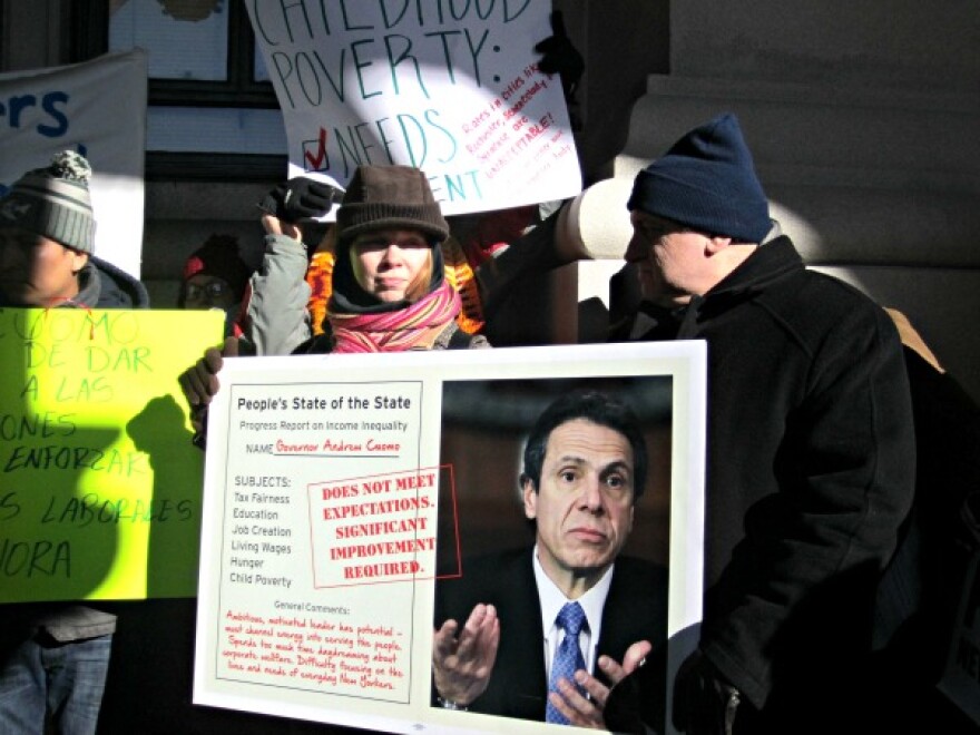 protesters bundled up outdoors with signs criticizing governor Andrew Cuomo