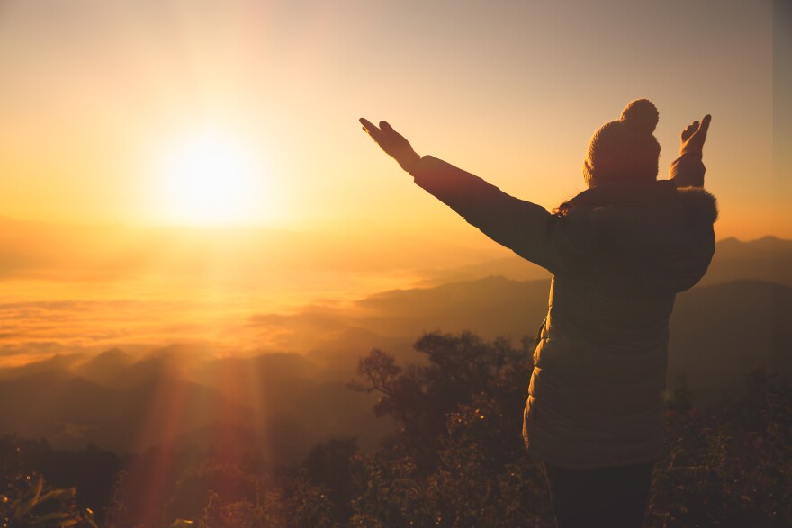 Copy space of silhouette woman raise hand up on top of mountain and sunset background. Freedom feel good and travel adventure holiday concept. Religious beliefs
