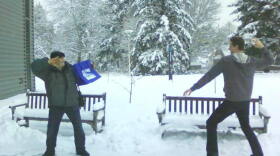 KPLU host Kevin Kniestedt takes aim with a snowball as Dick Stein takes refuge behind the KPLU tote bag.