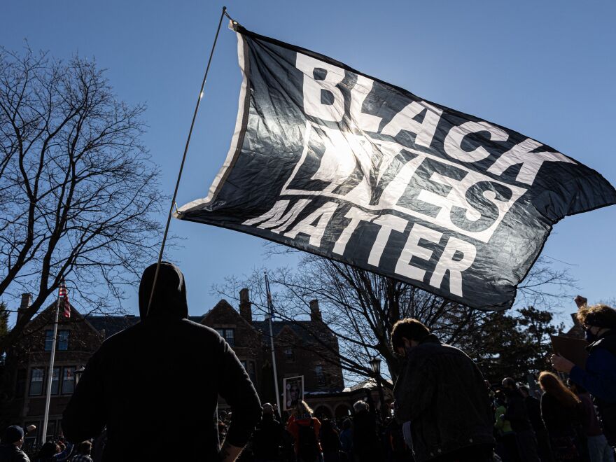 A man holds a Black Lives Matter flag during the protest "Families Supporting Families Joins Mass Action 4 George Floyd Justice 4 All Nationwide Protest" in St.Paul, Minnesota, on March 6, 2021.