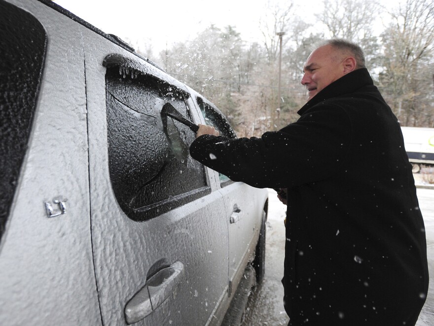 Dr. Rick Coslett scrapes a coating of ice of his vehicle in Kingston Township, Pa., on Friday.