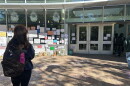 A student stands outside the Batten Arts and Letters building at Old Dominion University on Oct. 26, 2026, looking at signs and other tributes left as a memorial for a student who died at the building the week before.