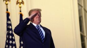 US President Donald Trump salutes from the Truman Balcony upon his return to the White House from Walter Reed Medical Center, where he underwent treatment for Covid-19, in Washington, DC.