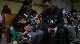 Venezuelan migrants Kimberly González and Denny Velasco and their children wait for a bus at Mission: Border Hope in Eagle Pass, Texas.
