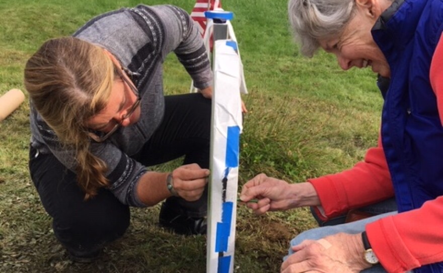  Karin Sprague and Sabra Field in October 2018, making a rubbing of Field's gravestone.