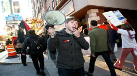 Jake Allen with Service Employees International Union (SEIU) speaks into a megaphone at a demonstration.