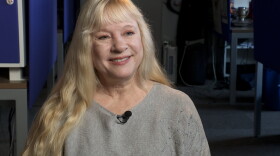 A blonde woman sits in a room.