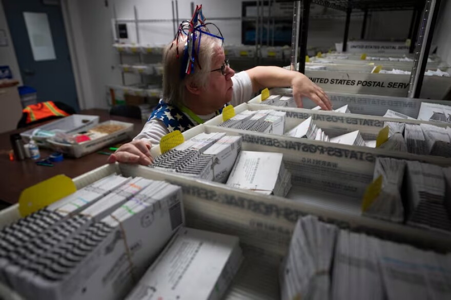 FILE - Election worker Wendy Wimer looks through vote-by-mail ballots for the presidential primary election, March 12, 2024, at the Clark County Elections Office in Vancouver, Wash.