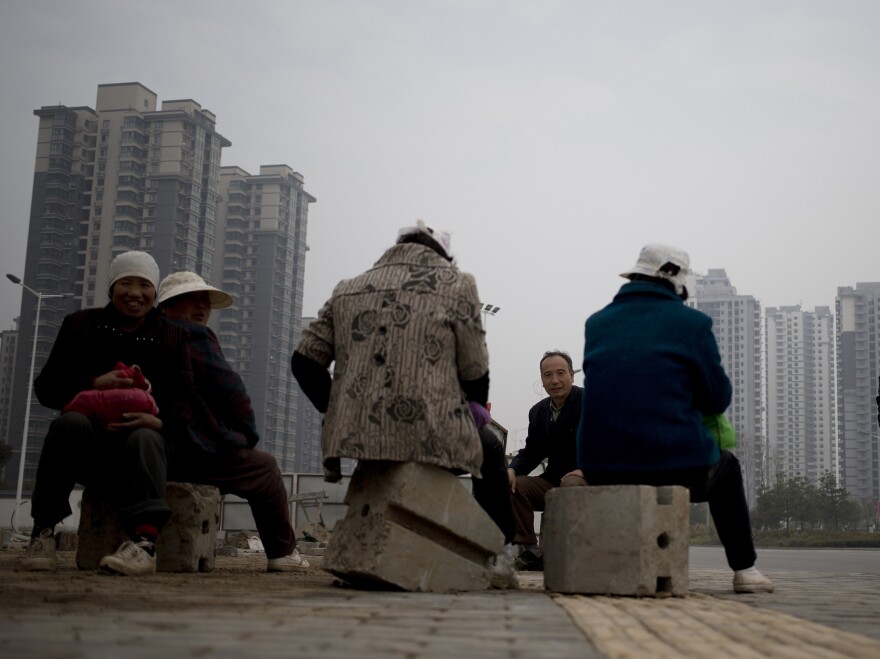 Migrant workers rest during their lunch break near newly built residential apartment buildings in Xi'an, in central China's Shaanxi province, on Nov. 6.