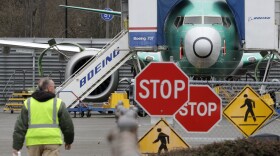 A Boeing worker walks near a 737 Max jet on Monday in Renton, Wash. Boeing said it will suspend production of the troubled jetliner in January.
