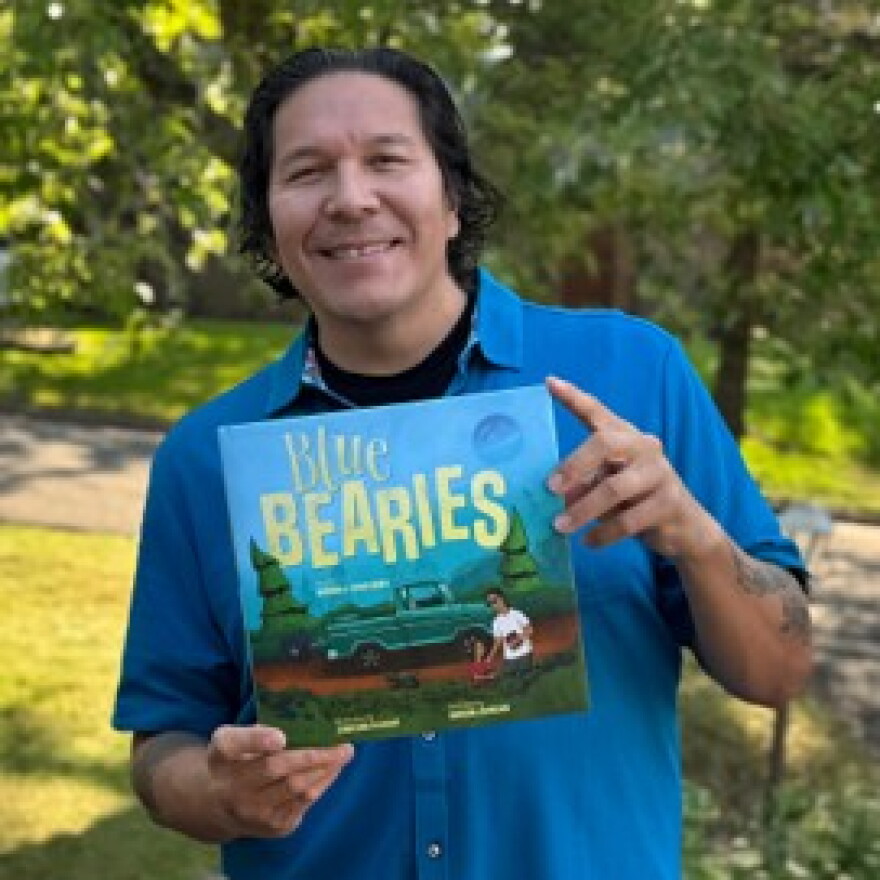 Jonathan Thunder outdoors holding the book "Blue Bearies."