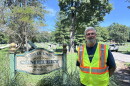 A man in a neon safety vest stands next to a sign that says, "Batavia Union Cemetery."