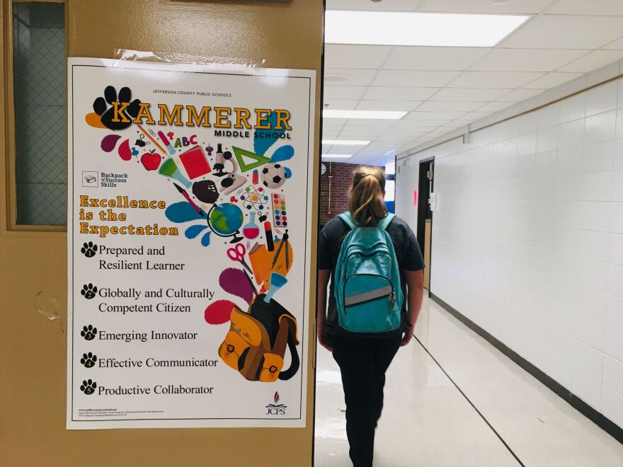 Eighth grader Mallory Blocker walks past a poster describing the Backpack of Success Skills Program at Kammerer Middle School.