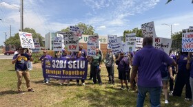 A group of protestors wearing purple shirts and holding up signs in both English and Spanish, asking for fairer salaries.
