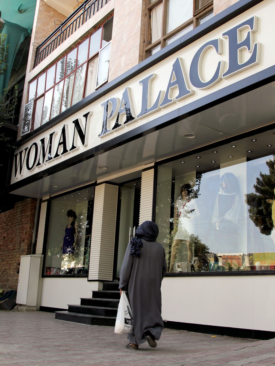 An Afghan woman walks past Woman Palace, which recently opened in Kabul. Despite the country's poverty and traditional, modest dress, stores catering to wedding gowns and other upscale women's clothing are doing a brisk business.