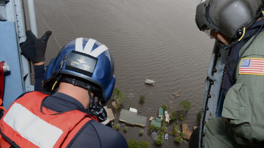 Coast Guard officers look down from helicopter