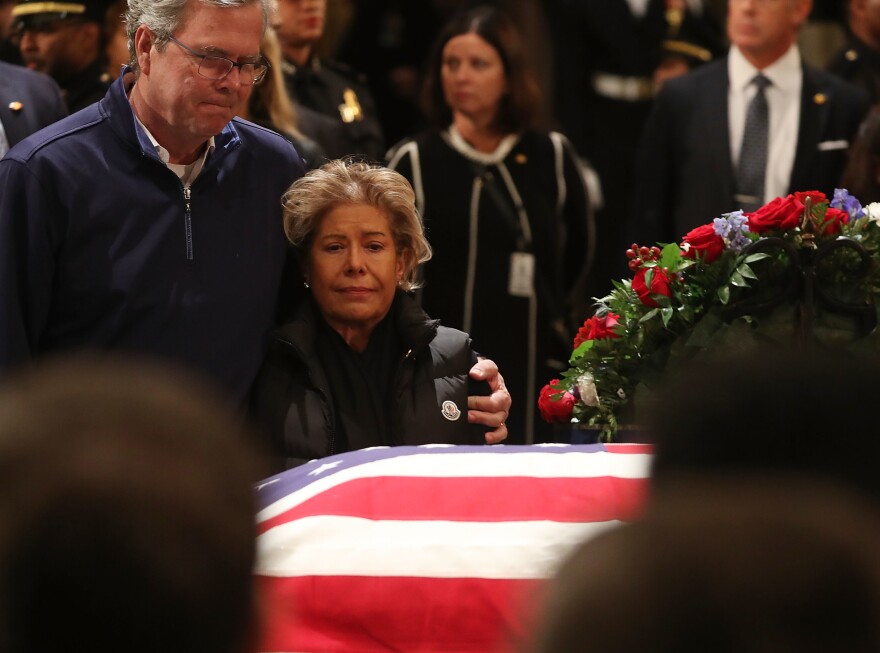 Former Florida Gov. Jeb Bush and his wife Columba Bush pay their respects in front of the casket of the late former President George H.W. Bush as he lies in state in the U.S. Capitol Rotunda Tuesday in Washington, D.C.