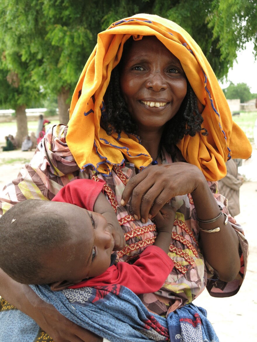 A mother and child at Muna informal displaced people's settlement. They're among 13,000 people at the camp, far from home after fleeing Boko Haram violence. They're calling for more Nigerian government and relief aid amid a malnutrition emergency and the lean pre-harvest farming season.