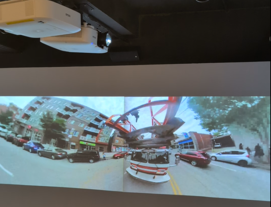 A video still of a fire truck. Projectors are on the ceiling.