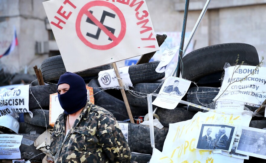 A pro-Russian activist guards the Regional Administration building on April 18 in Donetsk, Ukraine. The placard behind him says, "No to Fascism."