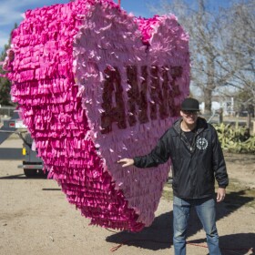 Lonnie Anderson showing off a giant heart-shaped piñata on a crane.