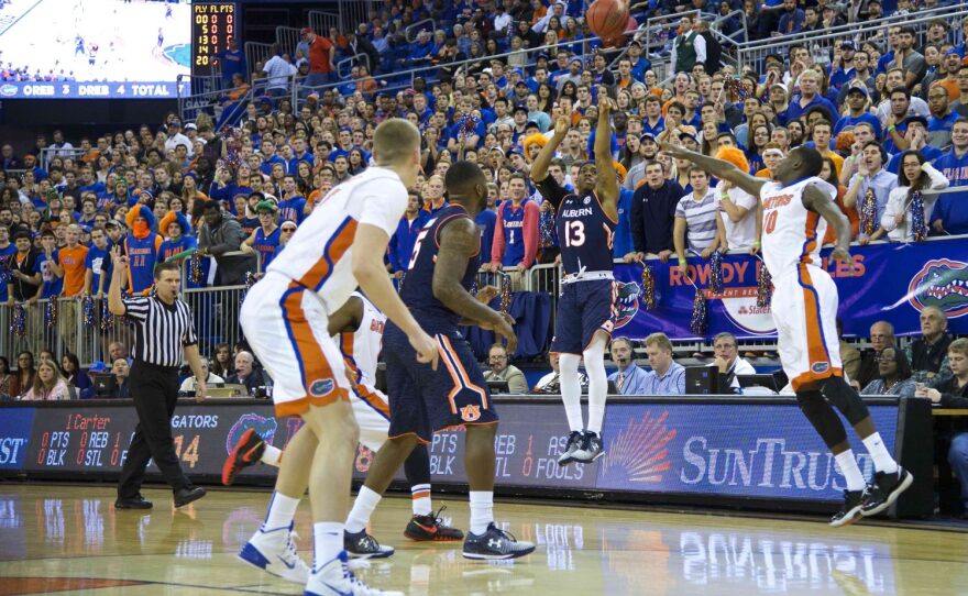 Auburn's Tahj Shamsid-Deen releases a three-point shot as Gator defenders close in.